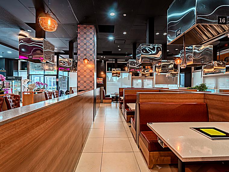 Warm wood booths with individual Korean BBQ grills at KOSOO Coquitlam